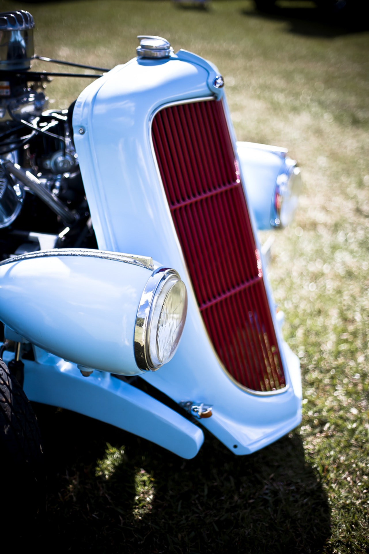 Classic light blue car front end with a polished red radiator grille